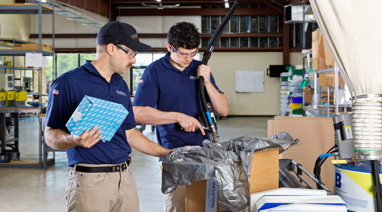 Two IAC technicians packing parts at the warehouse table