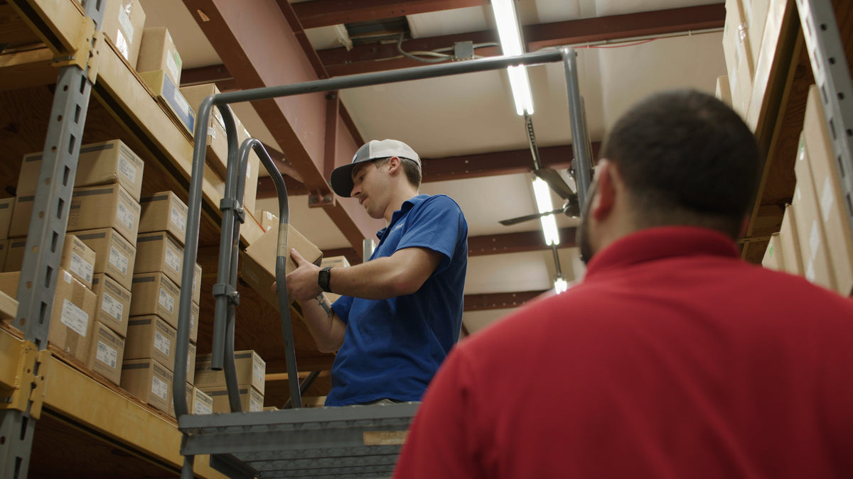 IAC technician on a ladder in the Raleigh warehouse